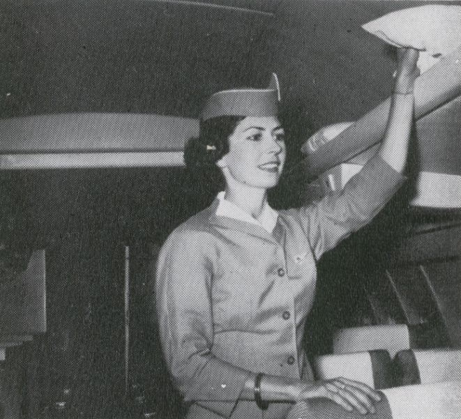 1959 A Pan Am stewardess reaches for a pillow in the cabin of a Boeing 707.